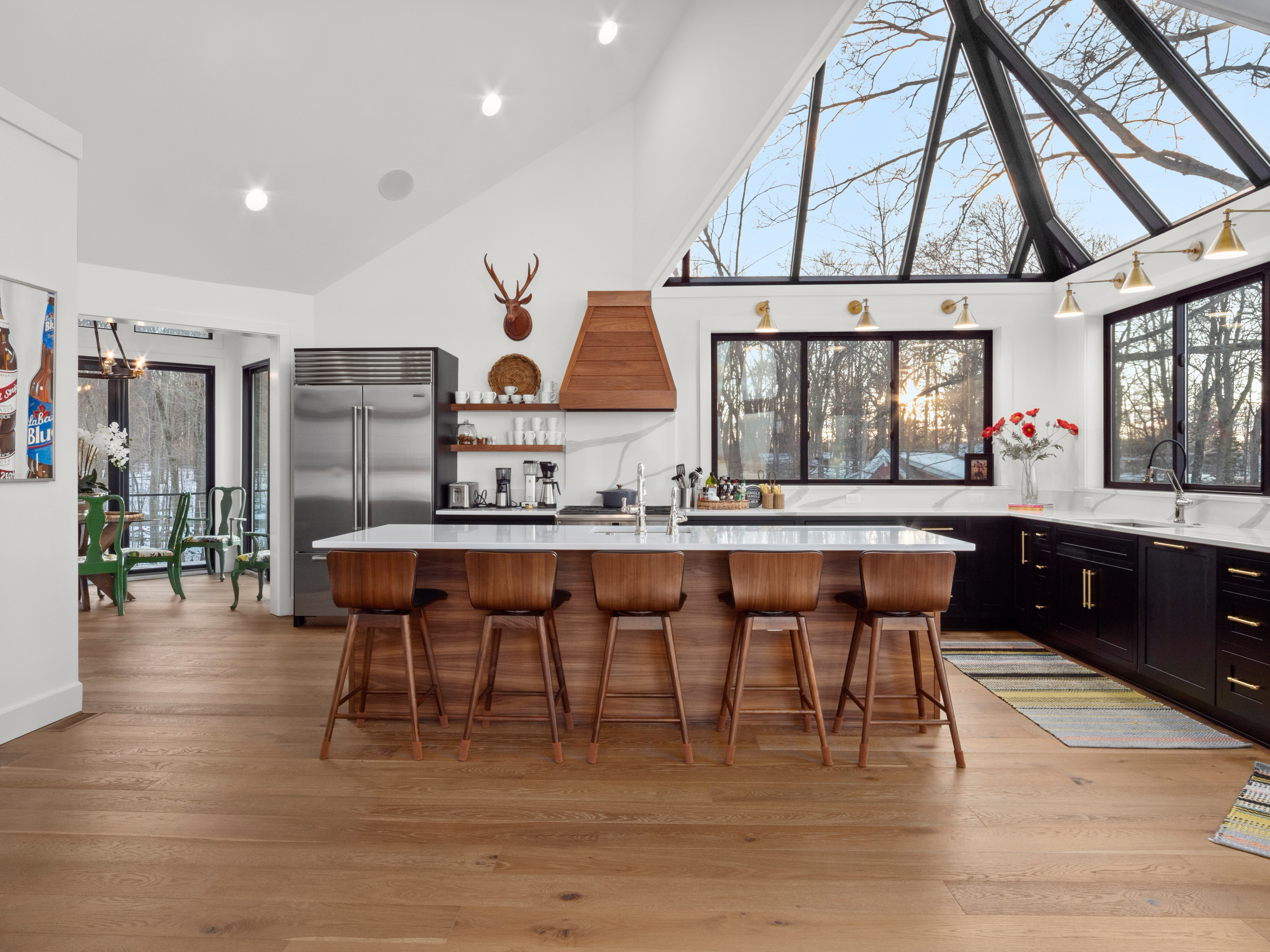 A bright custom kitchen with warm walnut cabinetry, black accents and dramatic windows