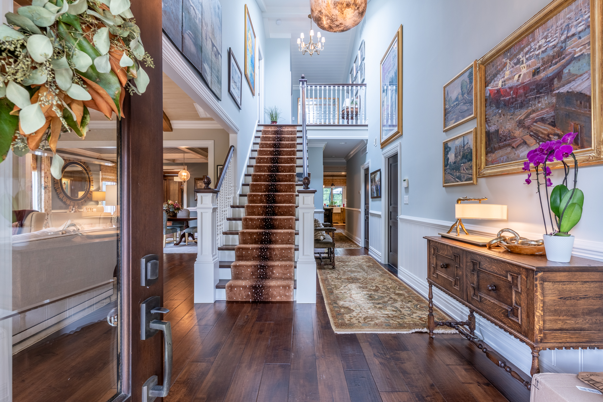 Mallard Cove entry with a central staircase, collected paintings and antique furnishings